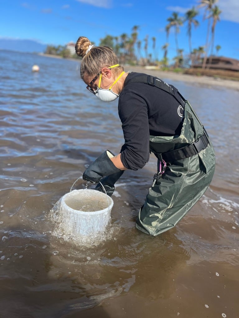A volunteer knee deep in water taking a sample