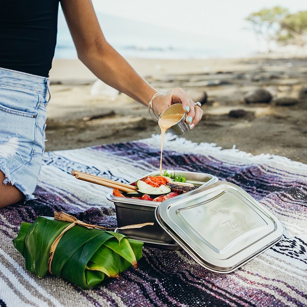 Woman enjoying a lunch on the beach using reusable food containers